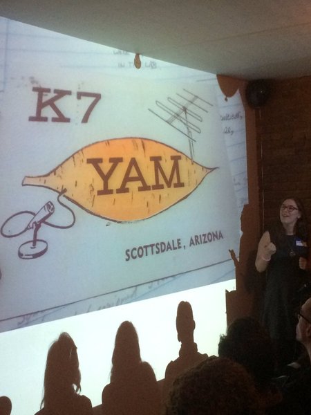 Elana Hashman pointing at a K7YAM QSL card, which features a yam
